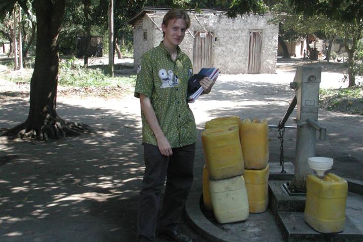 Marc Jeuland stands in front of a hand water pump in Mozambique.