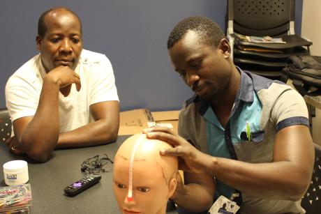 Christopher Komakech demonstrates how to place electrodes for an EEG exam
