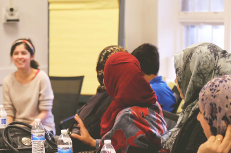 Project team member Rayan Kaakati, a medical student, talks with refugees living in Durham.