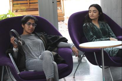 As part of the performance preparation, Nisha Uppuluri (left) explains how her headphones represent one of the characters in the play while Mahnoor Nazeer looks on.